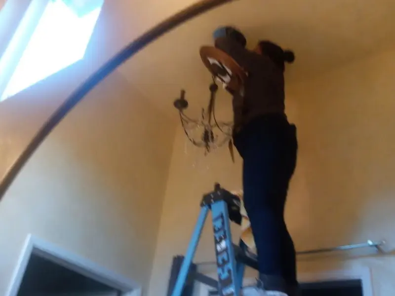 Electrician installing a chandelier in a Mount Healthy residence